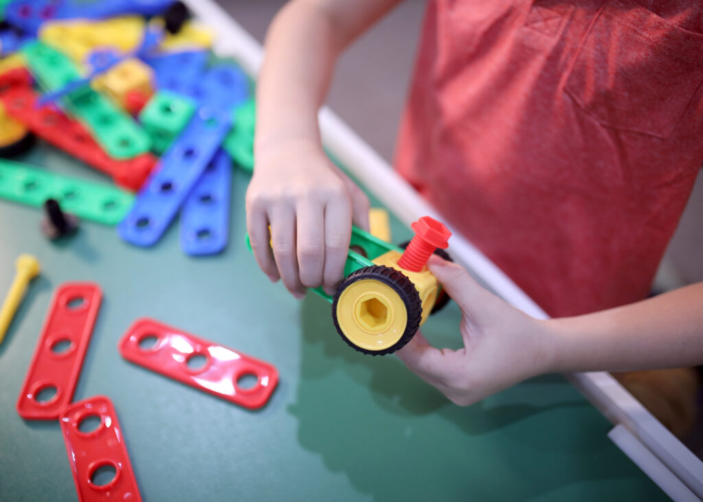 Child's hands building robotics at CLEAR.