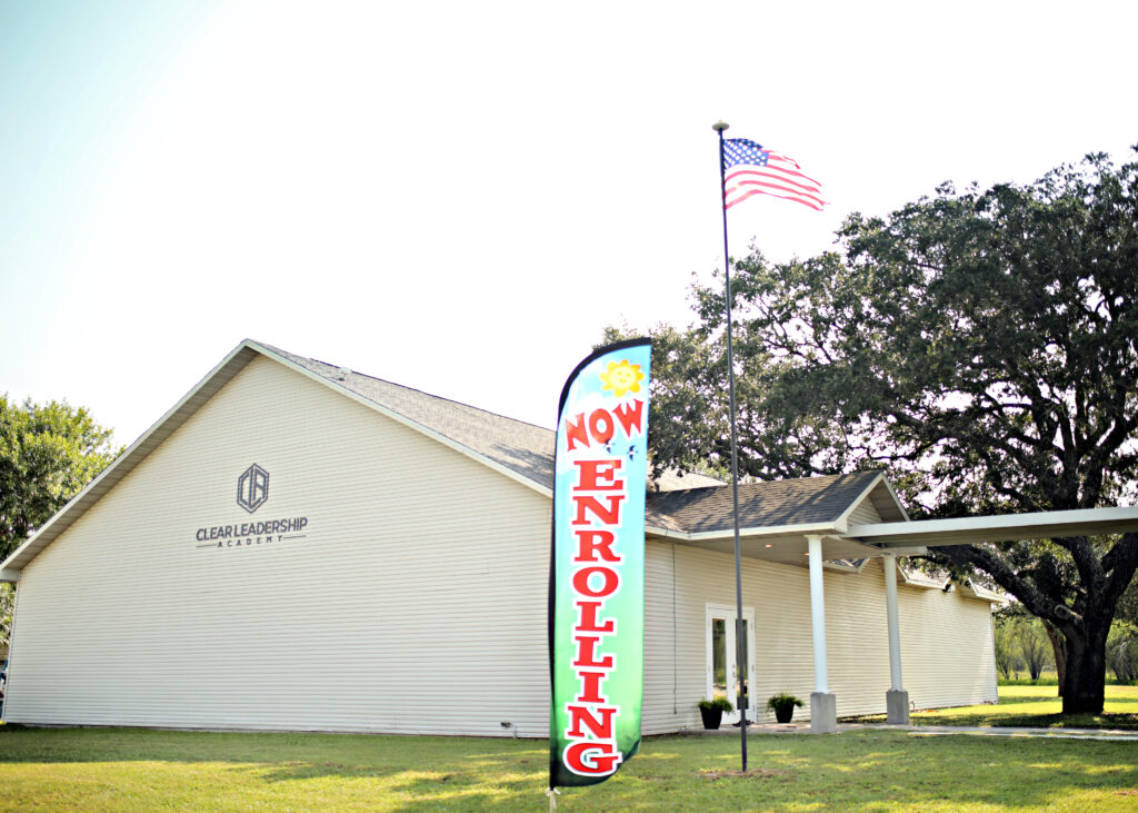 CLEAR Leadership Academy outside with enrollment flag.
