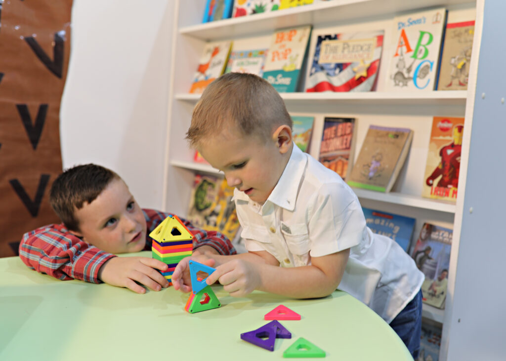 Kids at CLEAR building structures near a bookshelf.